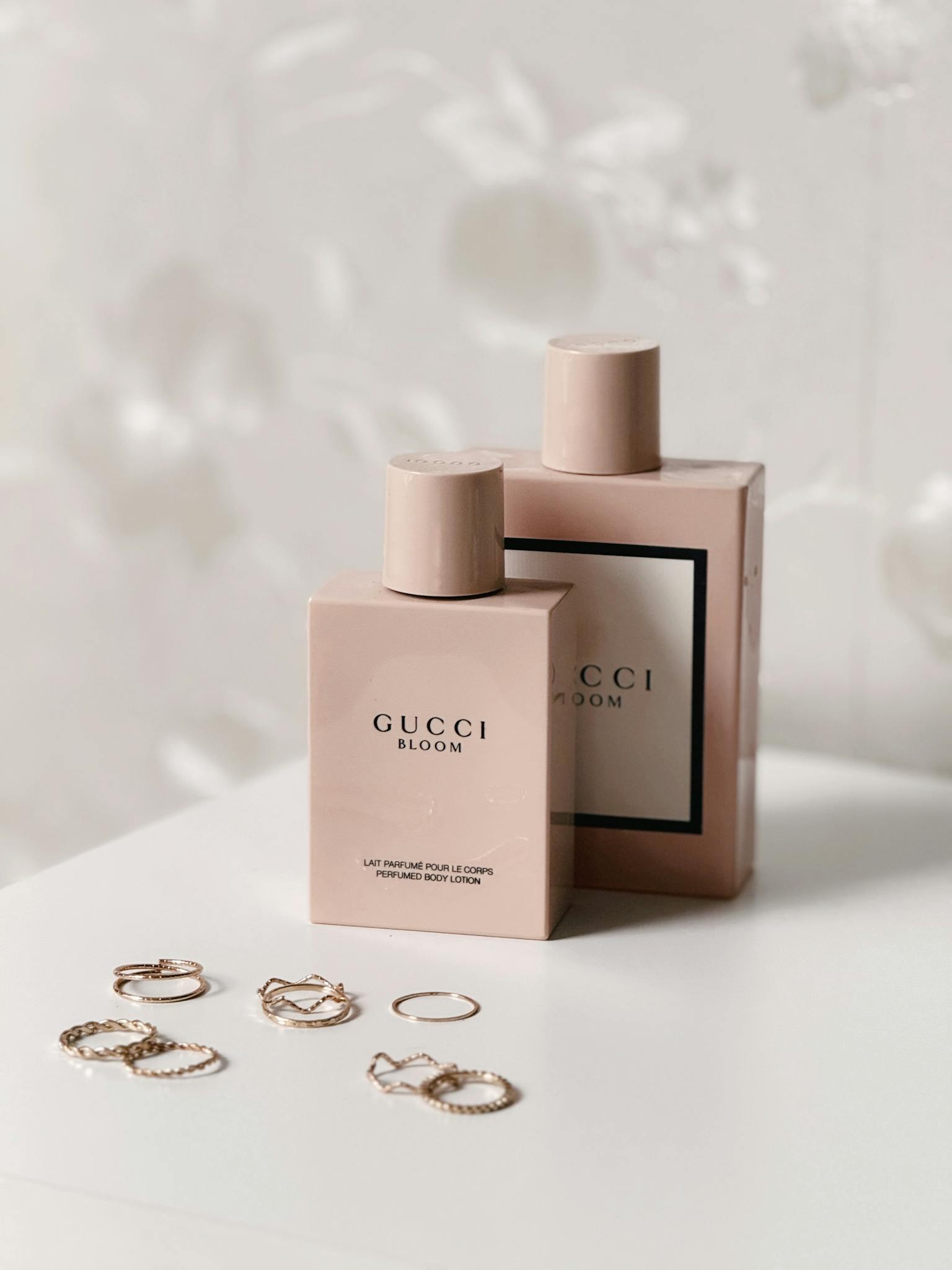 Luxurious Gucci Bloom perfume bottles with delicate jewelry in a soft, elegant setting.