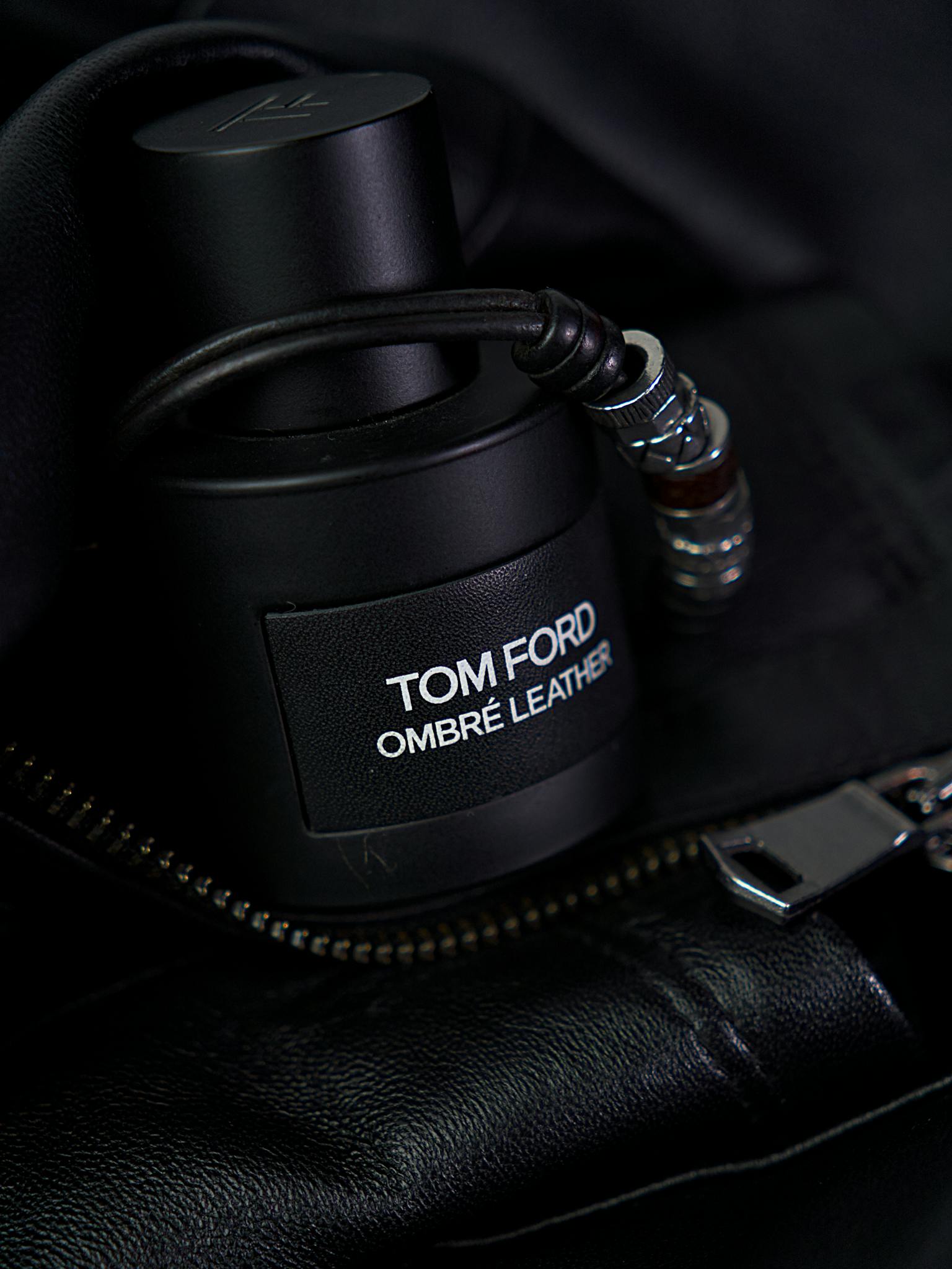 Tom Ford Ombré Leather fragrance bottle placed stylishly on a black leather jacket.